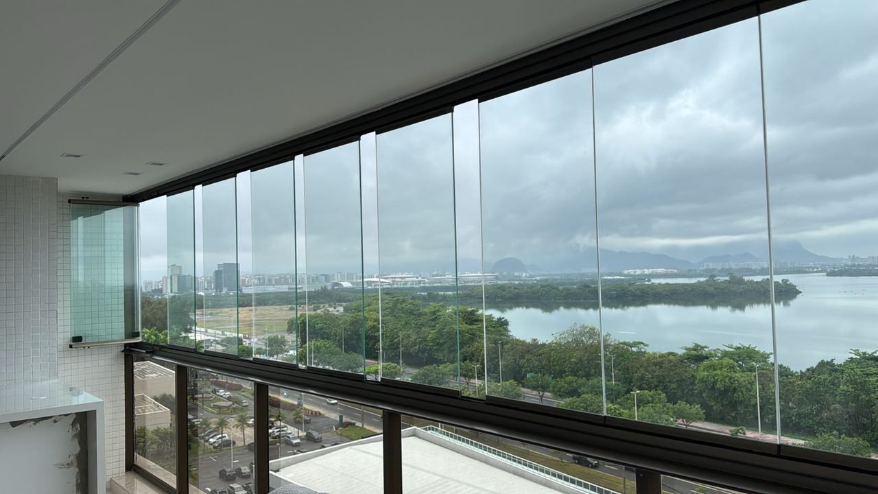 Varanda ampla com cortina de vidro em vão panorâmico, com vista para a lagoa